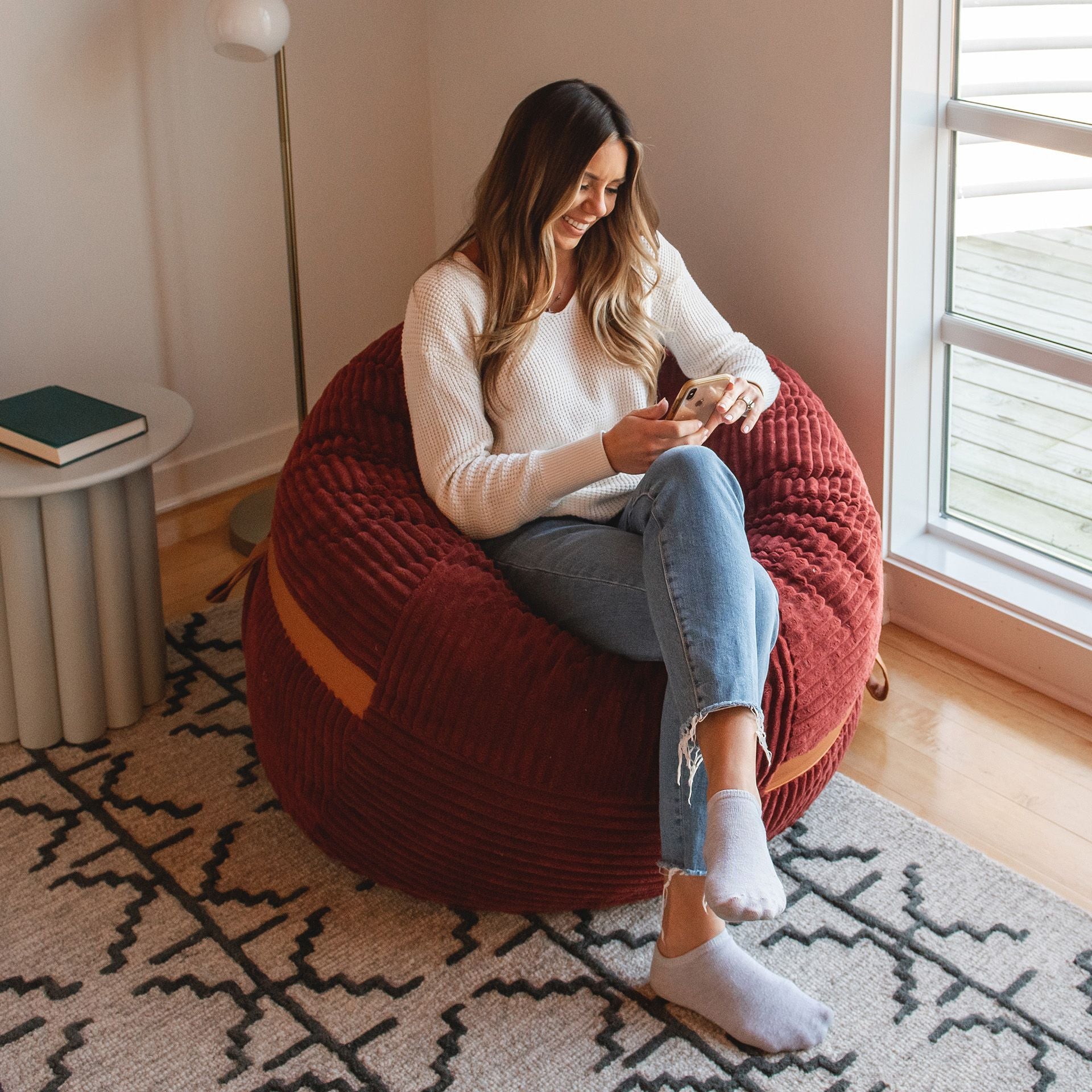 Woman watching videos on her bean bag chair #color_deep-terracotta-corded-plush
