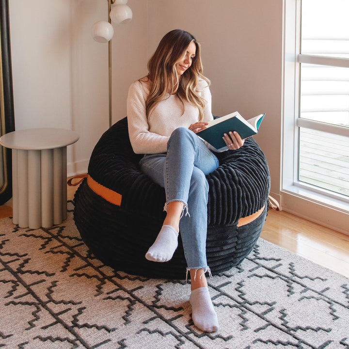 Woman reading on Fuf Bean Bag Chair with Foam Filling #color_black-licorice-corded-plush