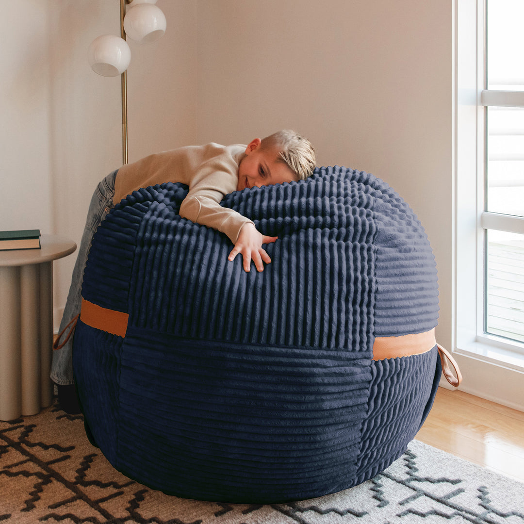 boy hugging Fuf Medium Foam-Filled Bean Bag Chair #color_midnight-blue-corded-plush