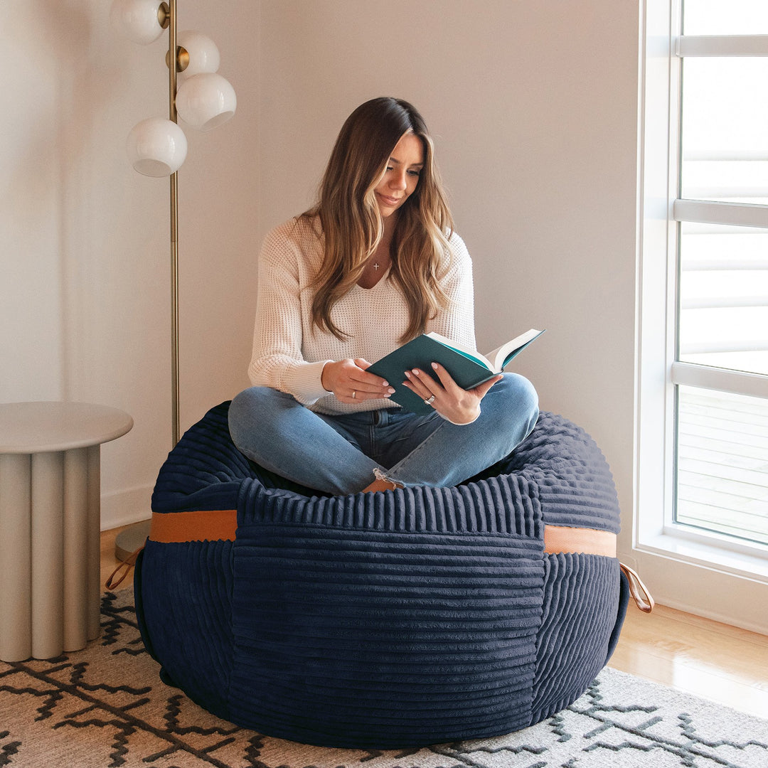 woman reading on Fuf Medium Foam-Filled Bean Bag Chair #color_midnight-blue-corded-plush
