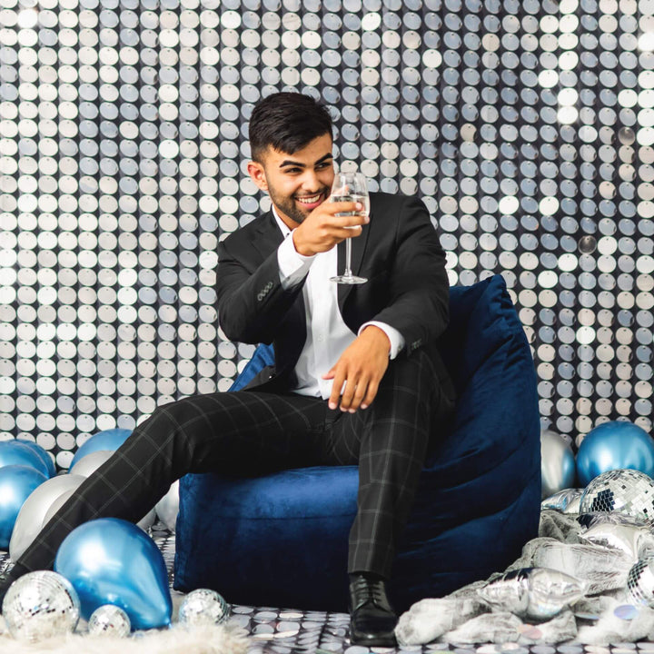 Aurora Chair bean filled man at party #color_deep-navy-velvet