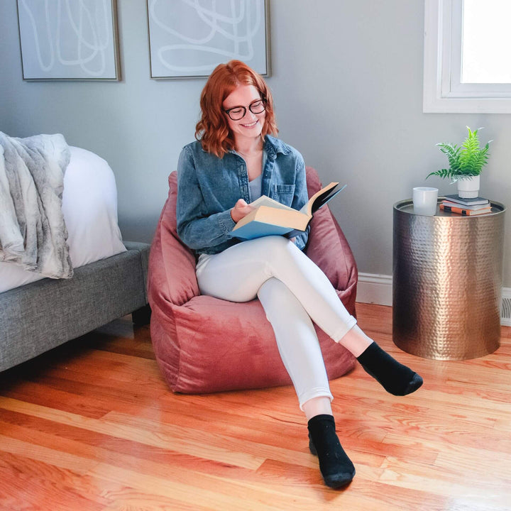 Pink Chair in room with woman reading #color_toasted-mauve-velvet