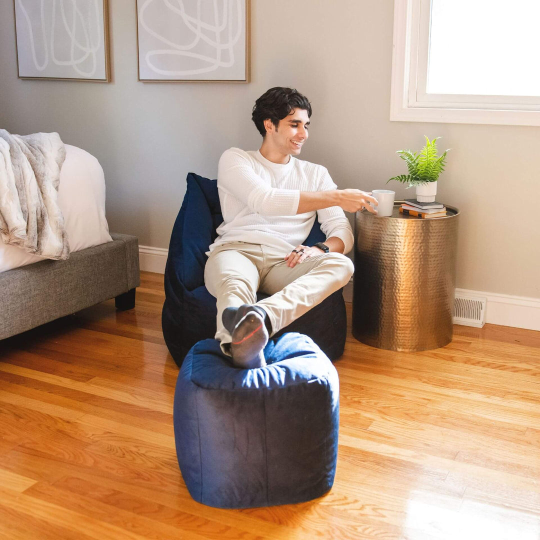 Aurora Bean Bag Chair with Ottoman in Blue man relaxing in room #color_deep-navy-velvet