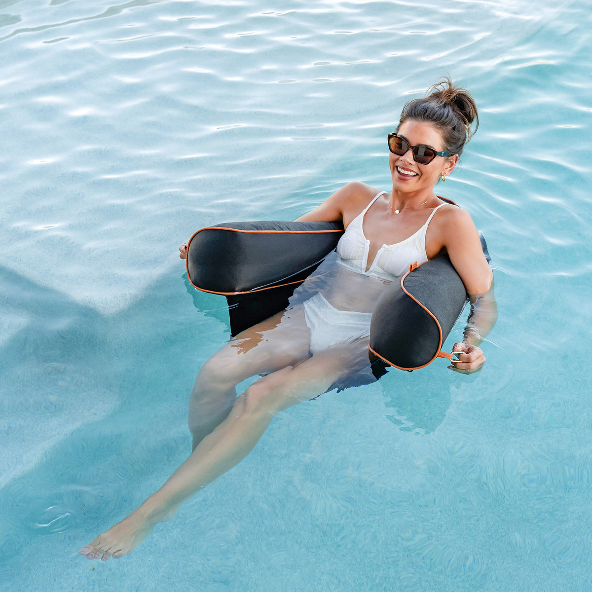 Woman in a pool holding an chair raft