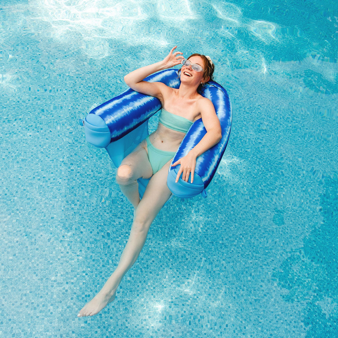 Sun bathing in the Shaka Sling XL pool float #color_ripple-blue