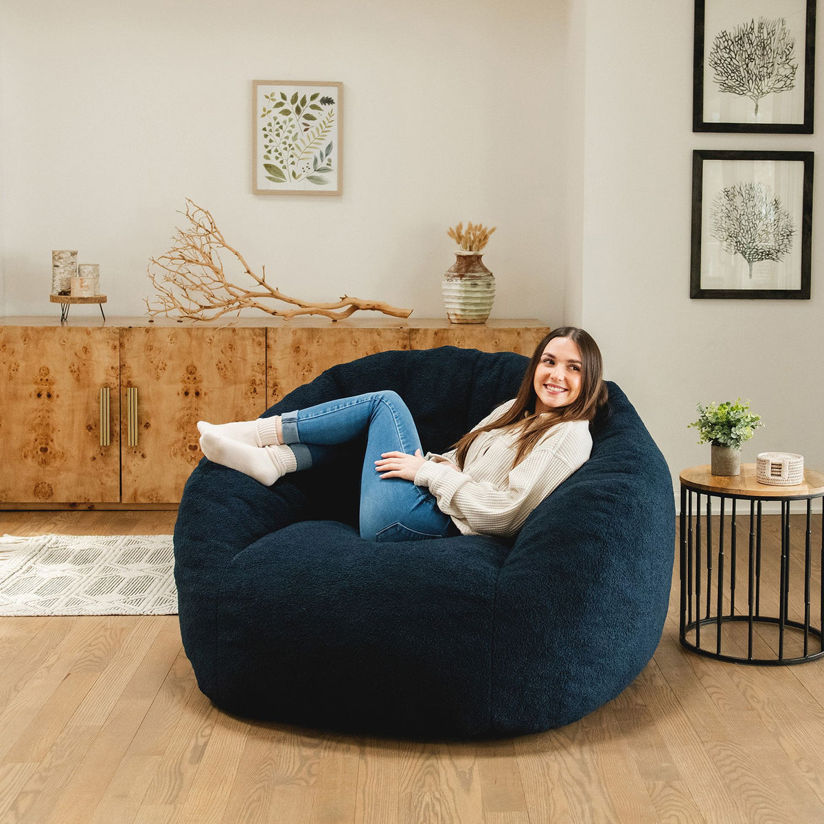 Woman relaxing in a blue cloud-like chair in the living room with small table near by