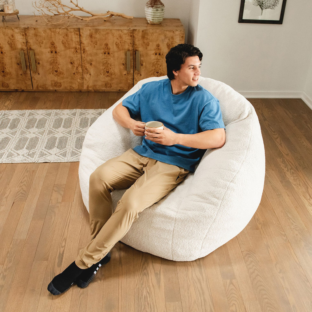 Man holding coffee cup in hand sitting in a chair in the living room