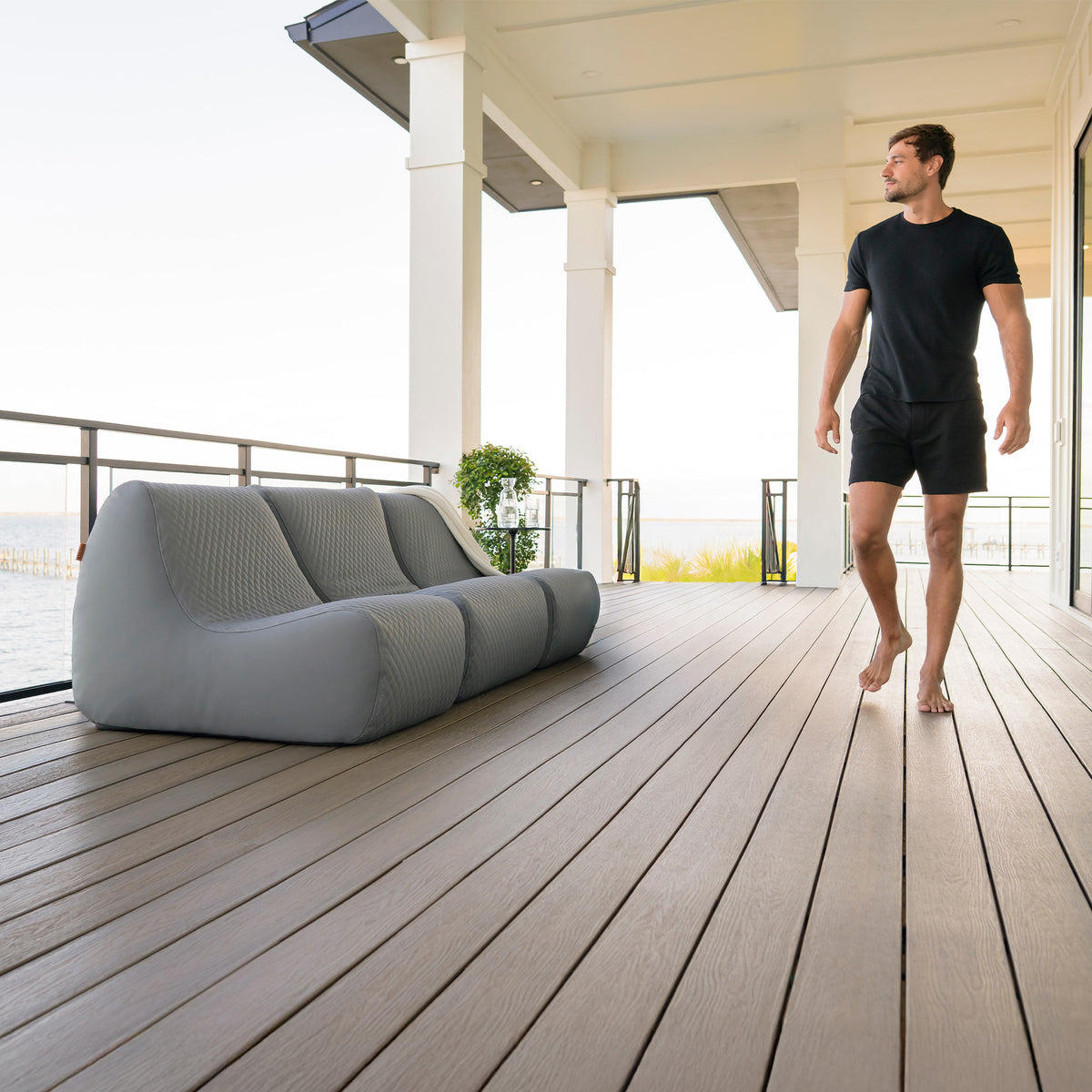 Man walking on a wooden deck with modern outdoor furniture