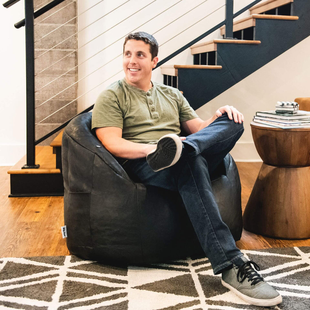 Milano Vibe Black Faux Leather Beanbag Chair man relaxing in living room #color_black-vegan-leather