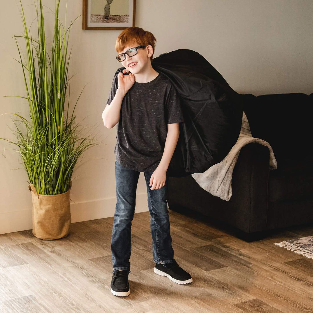 Boy carrying black indoor bean bag for kids #color_stretch-limo-black-smartmax