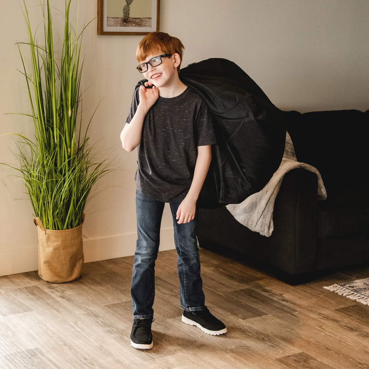 Boy carrying black indoor bean bag for kids #color_stretch-limo-black-smartmax
