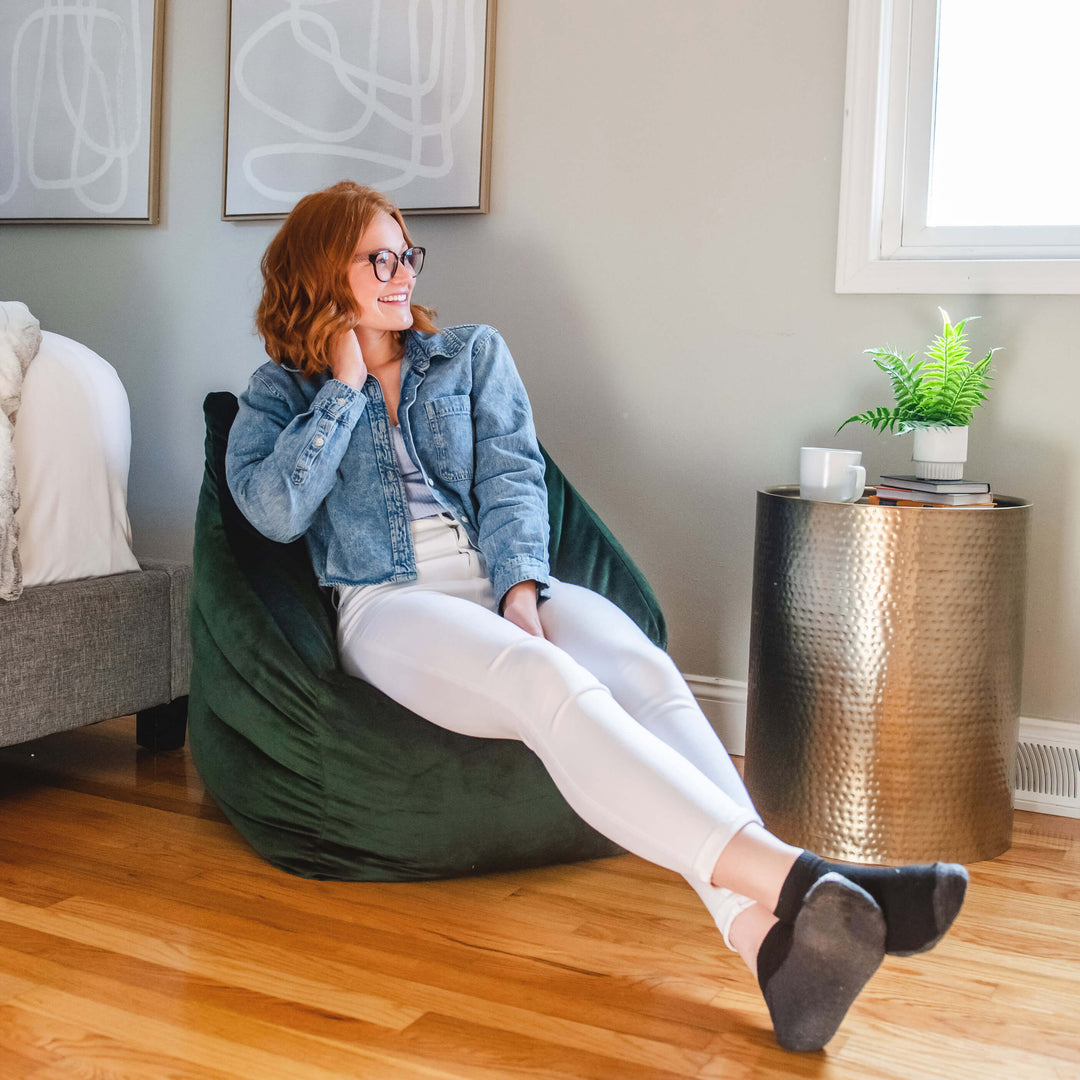 Girl sitting in a velvet bean bag chair in bedroom