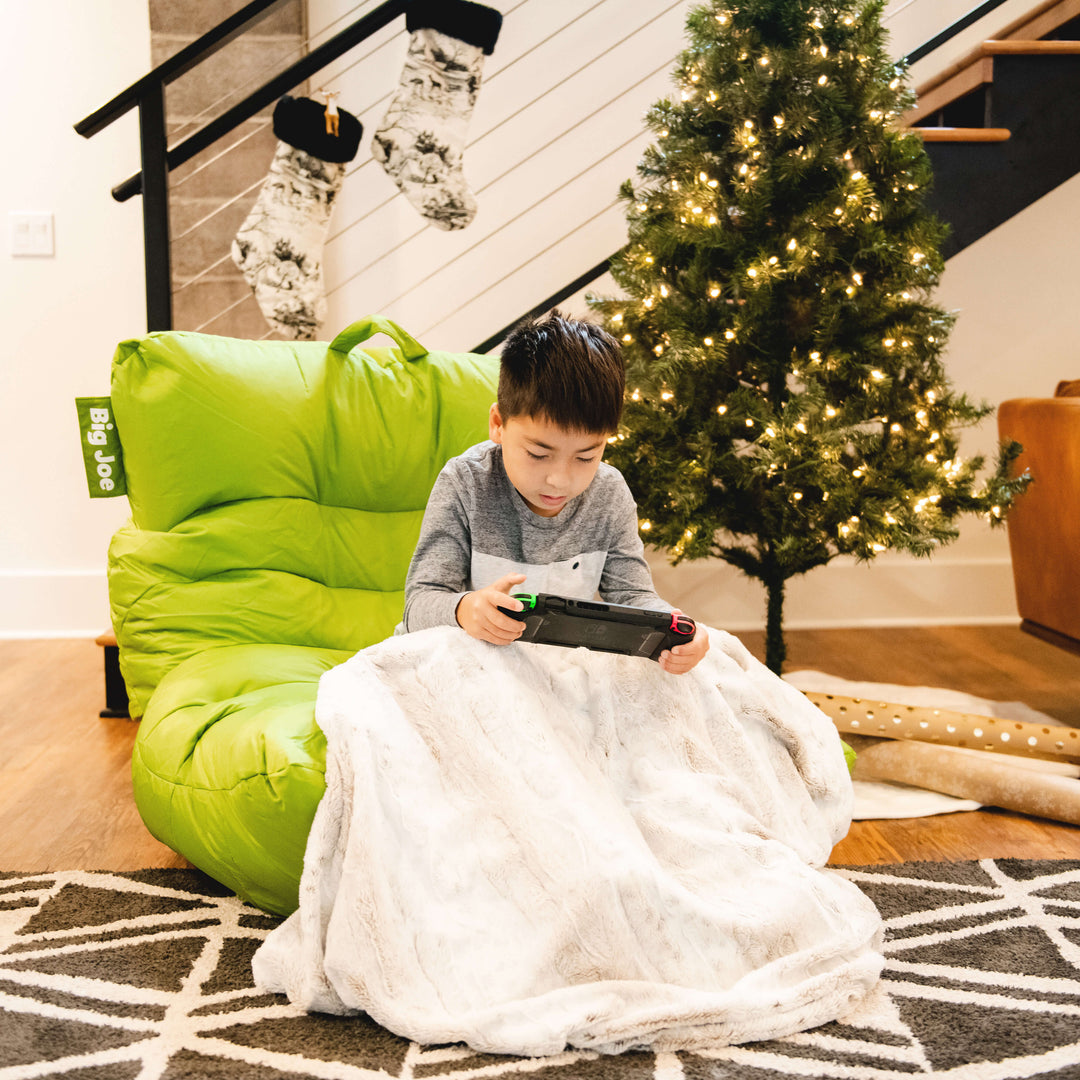 A small boy sitting in a bean bag chair playing a video game