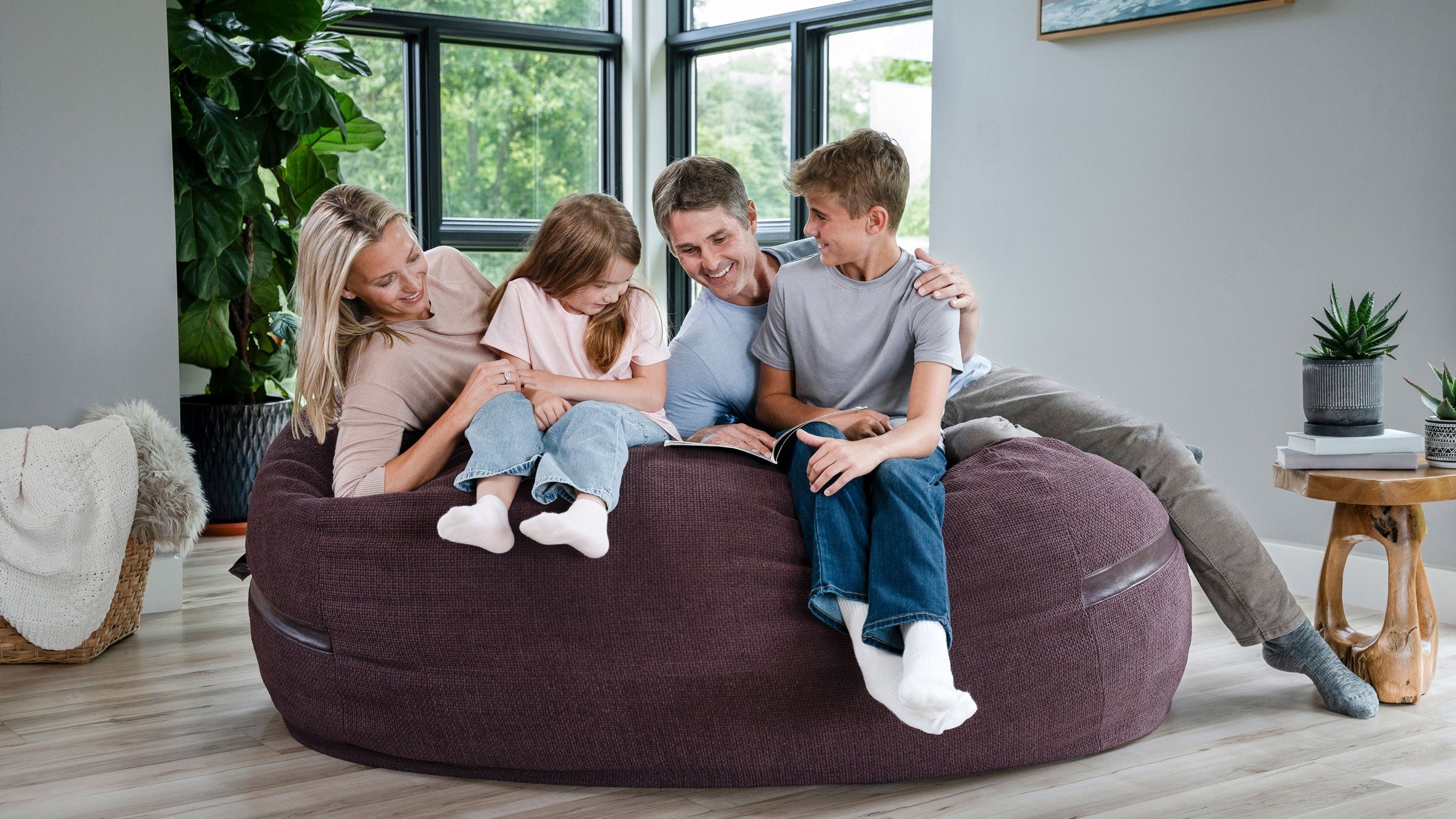 Family sitting on oversized foam beanbag chair loveseat.
