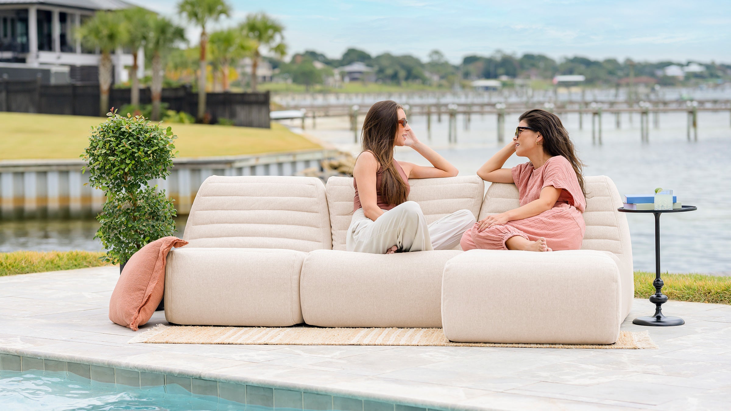 Woman relaxing on her patio in a outdoor bean bag chair with a sectional outdoor furniture set in the background