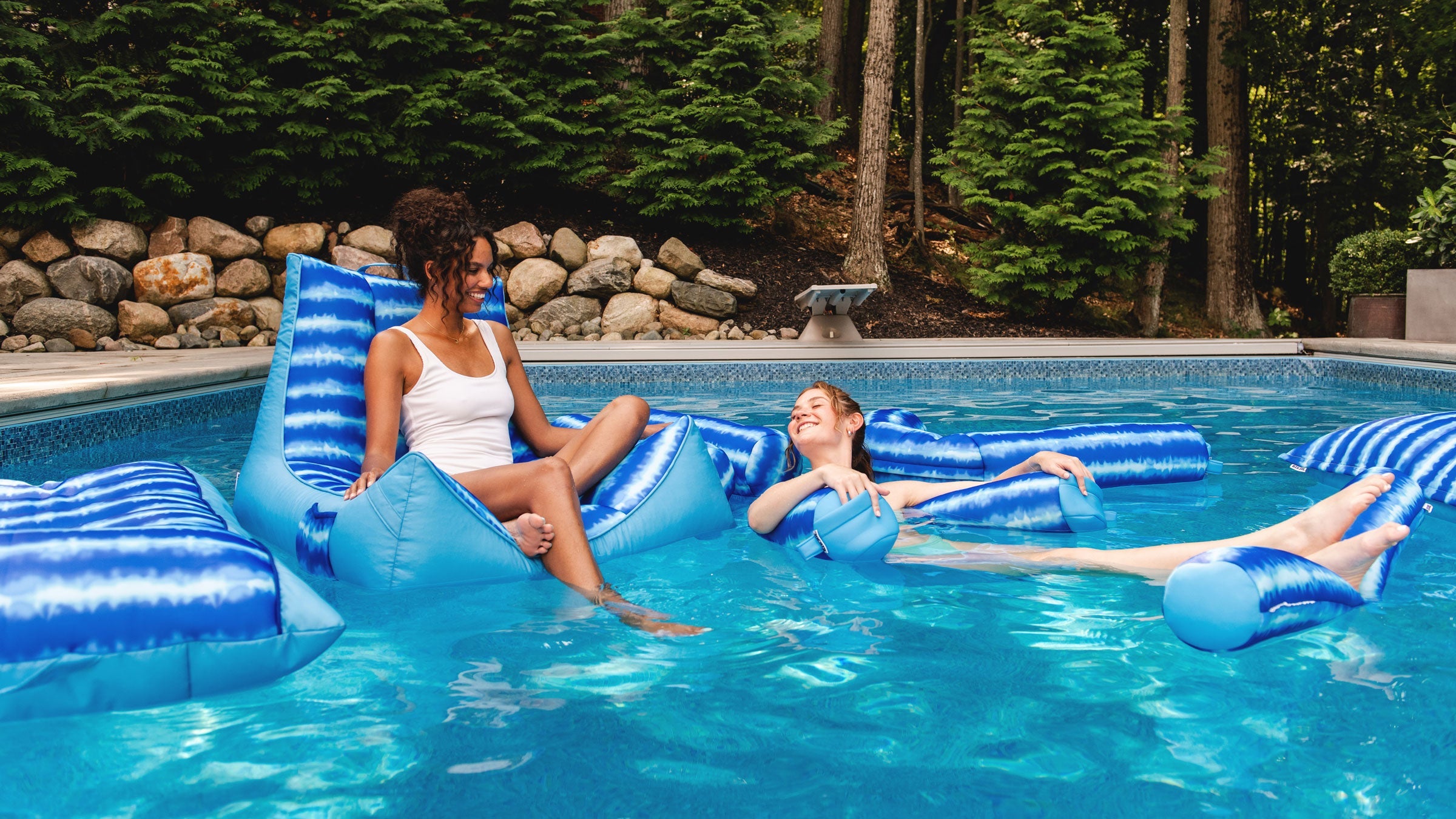 Two girls floating in the pool on Big Joe bean filled pool floats