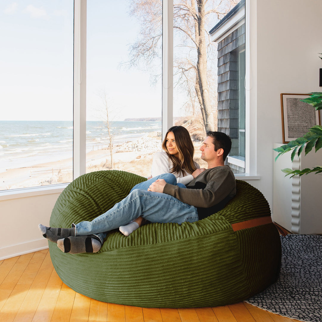 couple relaxing on the Big Joe Fuf XL Foam Beanbag Lounger Moss Green Corded Plush #color_moss-green