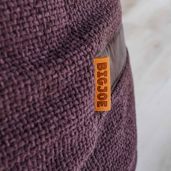 Close-up of a purple textured beanbag with a 'BIGJOE' label. #color_merlot-cloudweave