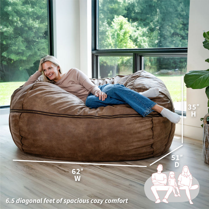 Woman relaxing on a large brown bean bag chair in a room with large windows. #color_coffee-soft-vegan-leather
