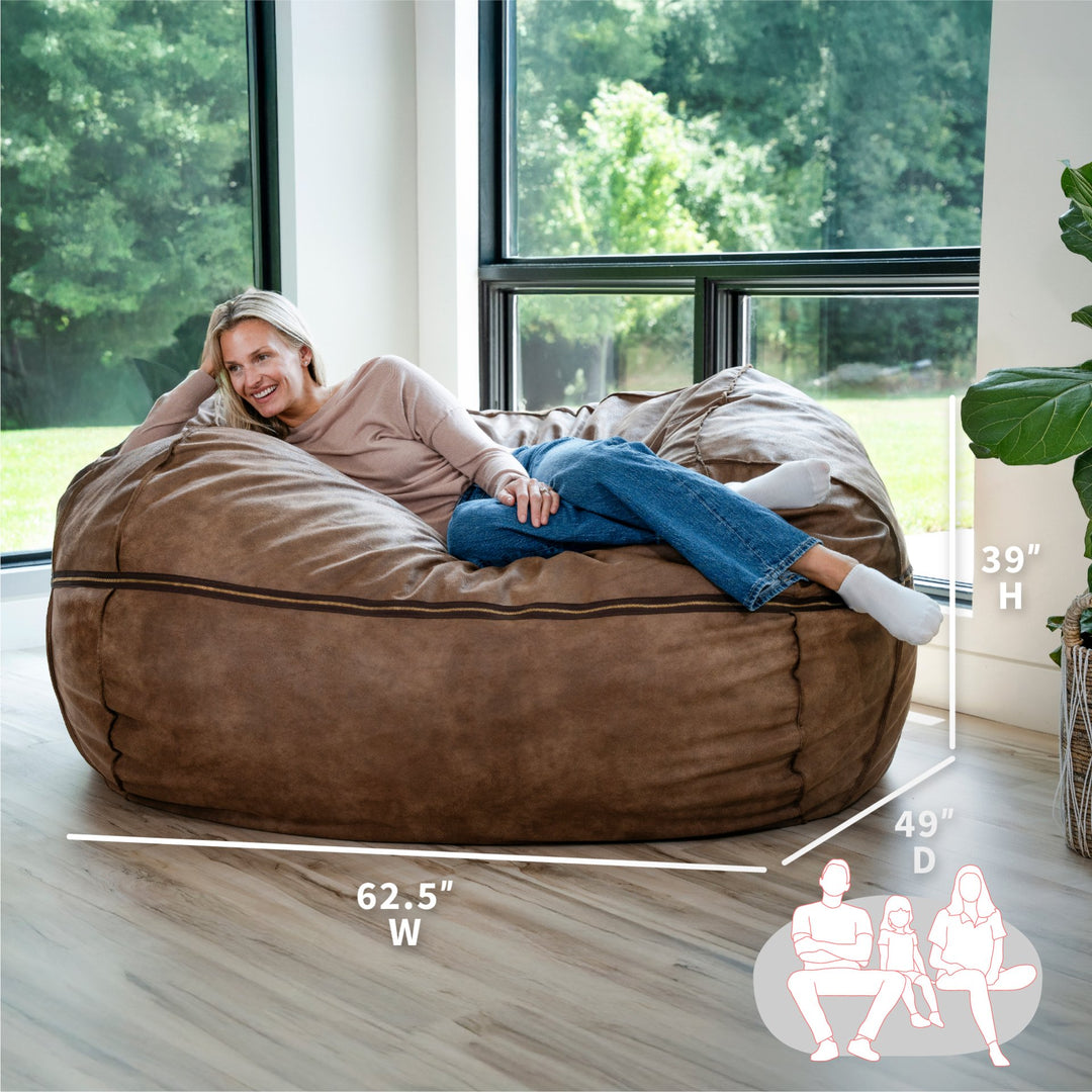 Woman sitting on a large brown bean bag chair with dimensions displayed. #color_coffee-soft-vegan-leather
