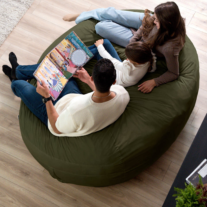 Family sitting on a large green bean bag reading a book together. #color_forest-green-velveteen