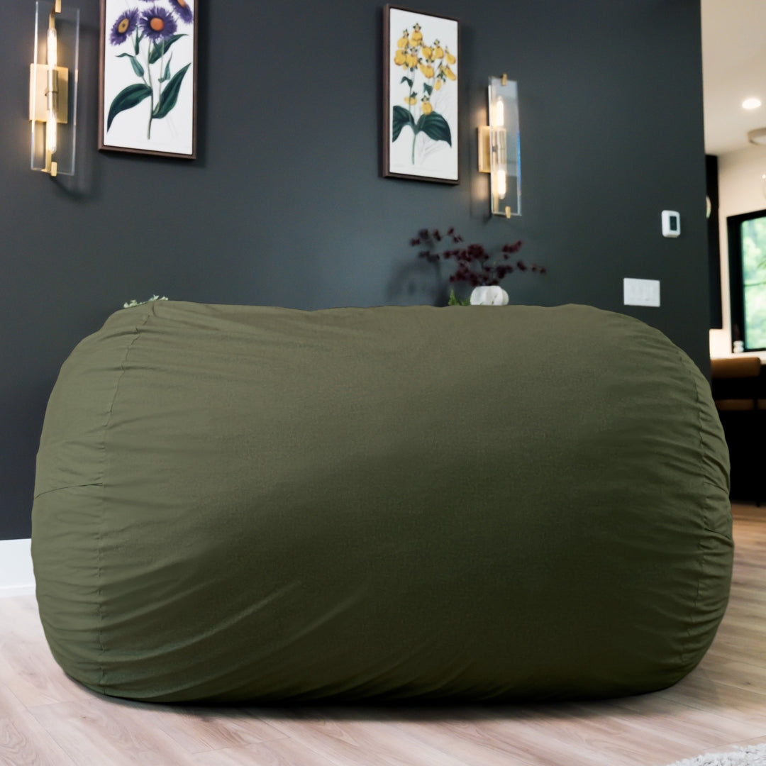 Large green bean bag chair in a room with dark walls and framed pictures. #color_forest-green-velveteen