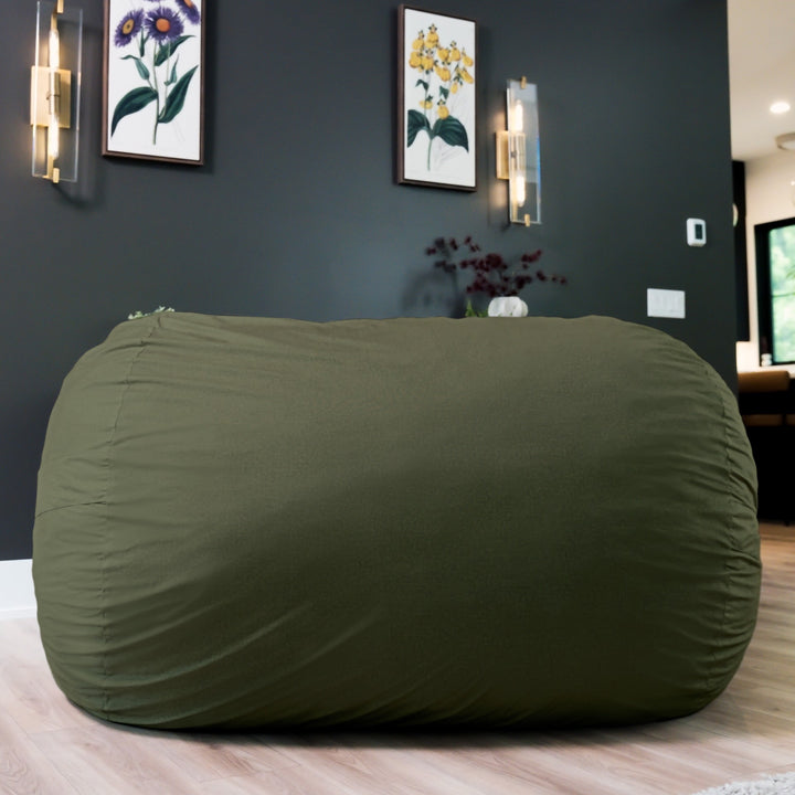 Large green bean bag chair in a room with dark walls and framed pictures. #color_forest-green-velveteen