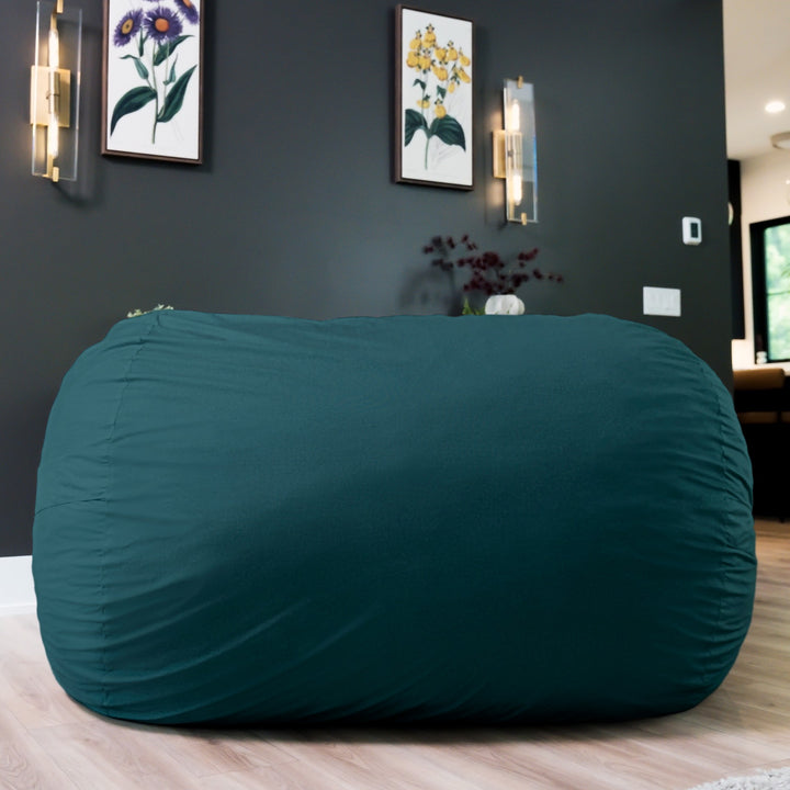 Teal bean bag chair in a room with dark walls and framed pictures. #color_deep-sea-velveteen