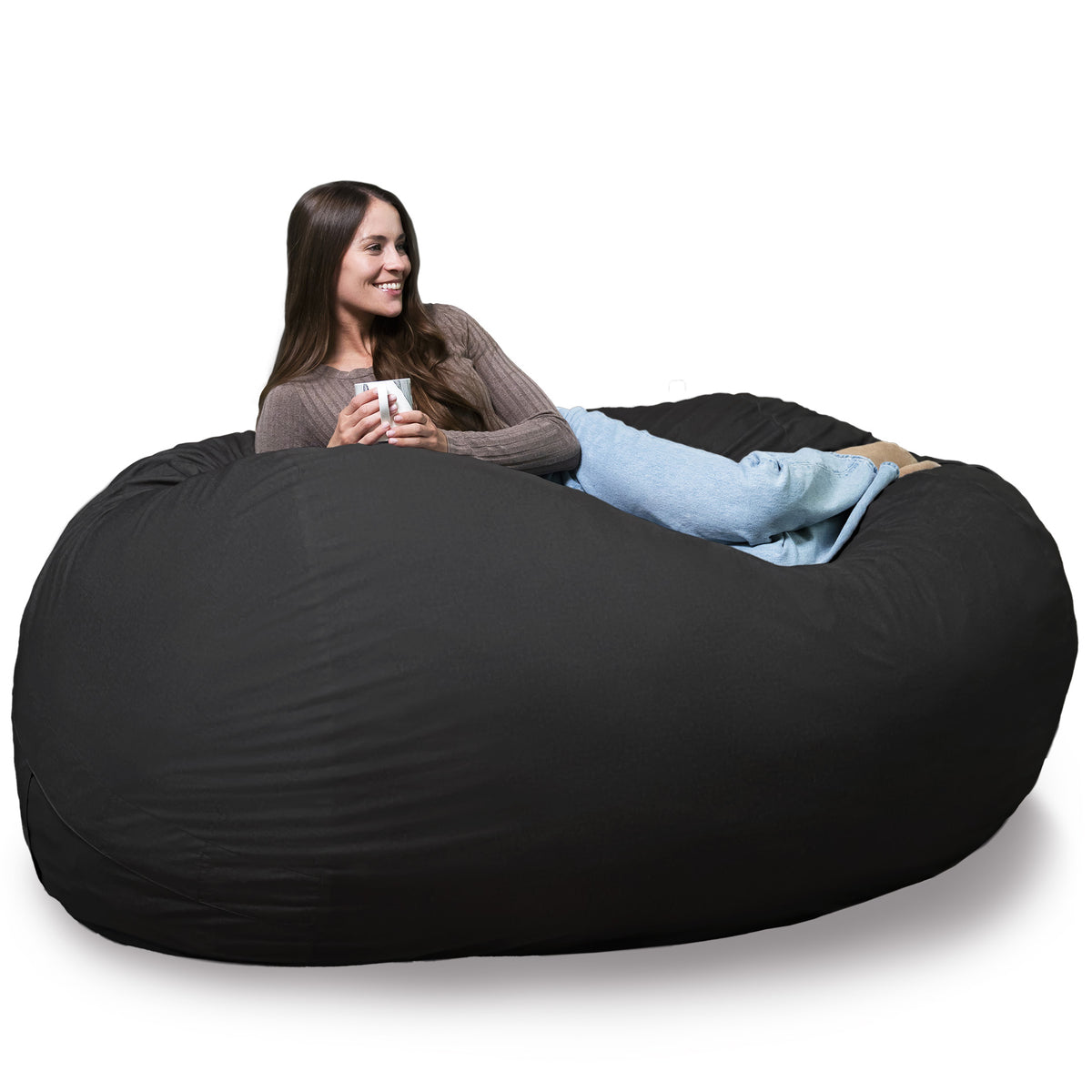 Woman sitting in a large black bean bag chair holding a cup. 