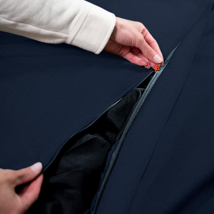 Person adjusting a zipper on a dark blue beanbag #color_cobalt-brushed-denim