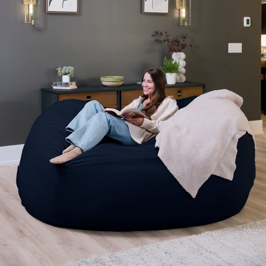 Woman reading a book on a large navy bean bag in a cozy living room. #color_cobalt-brushed-denim