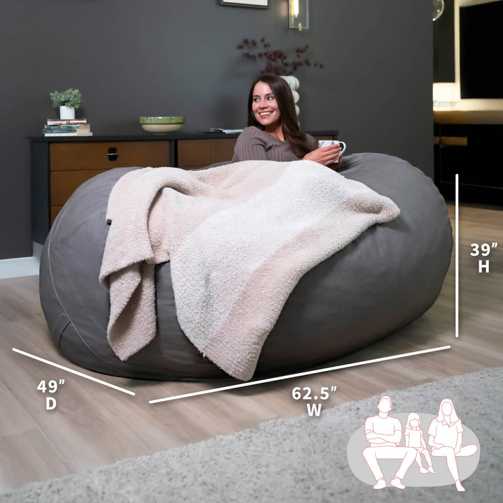 Woman sitting on a large gray bean bag chair with measurements and illustrations in a room. #color_fog-brushed-denim
