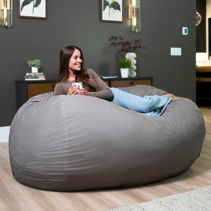 Woman sitting on a large gray bean bag chair in a modern living room. #color_fog-brushed-denim