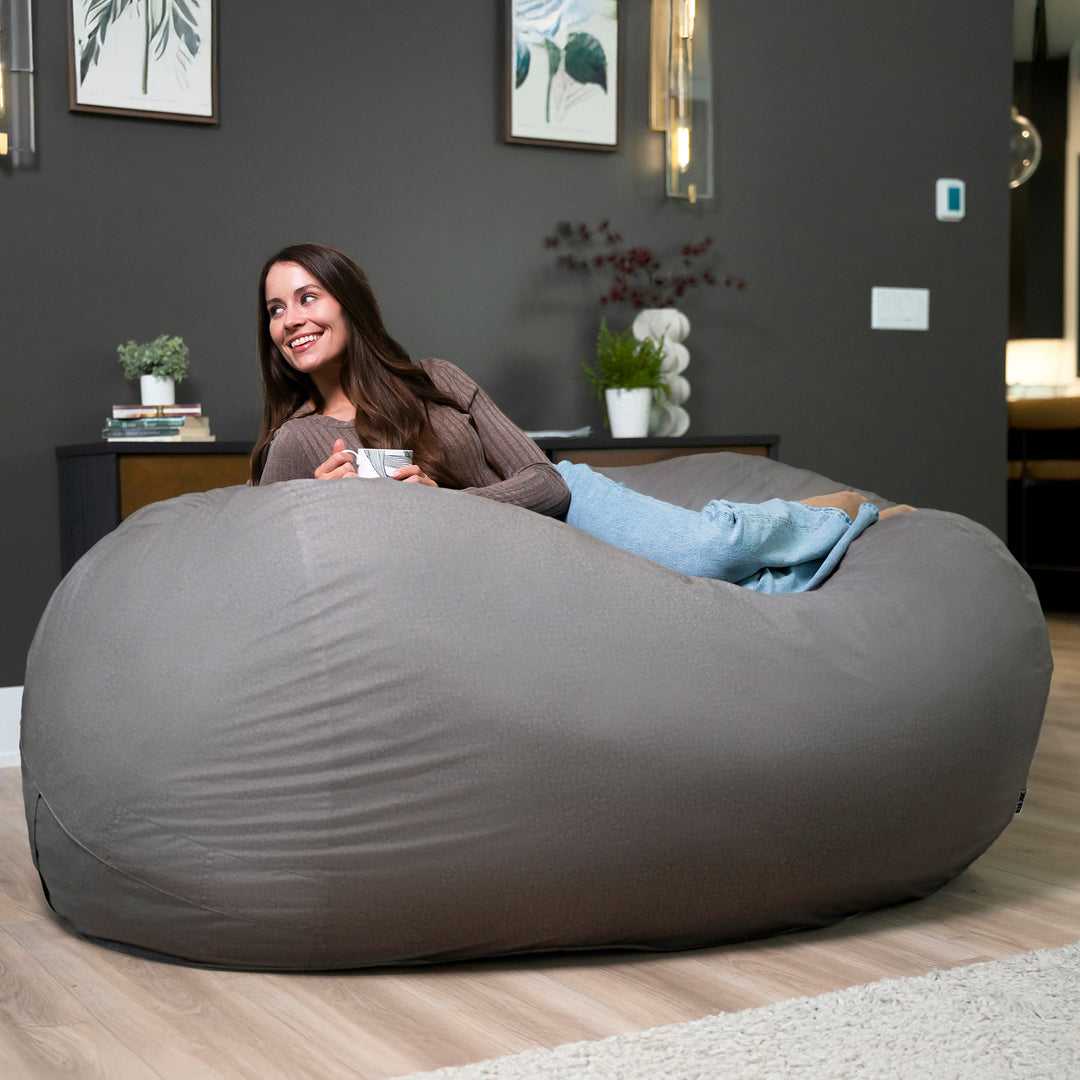 Woman sitting on a large gray bean bag in a modern living room. #color_fog-brushed-denim