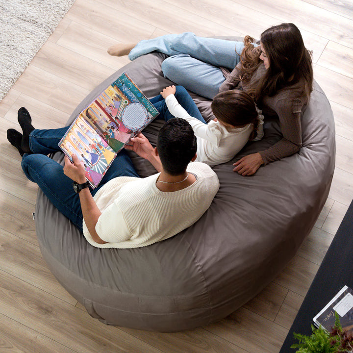 Family reading a book together on a large bean bag chair. #color_fog-brushed-denim