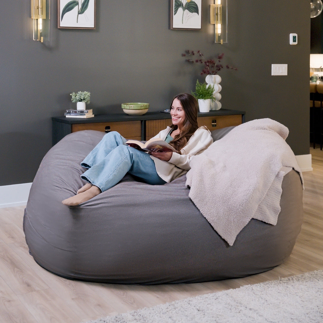 Woman sitting on a large gray bean bag chair in a modern living room. #color_fog-brushed-denim
