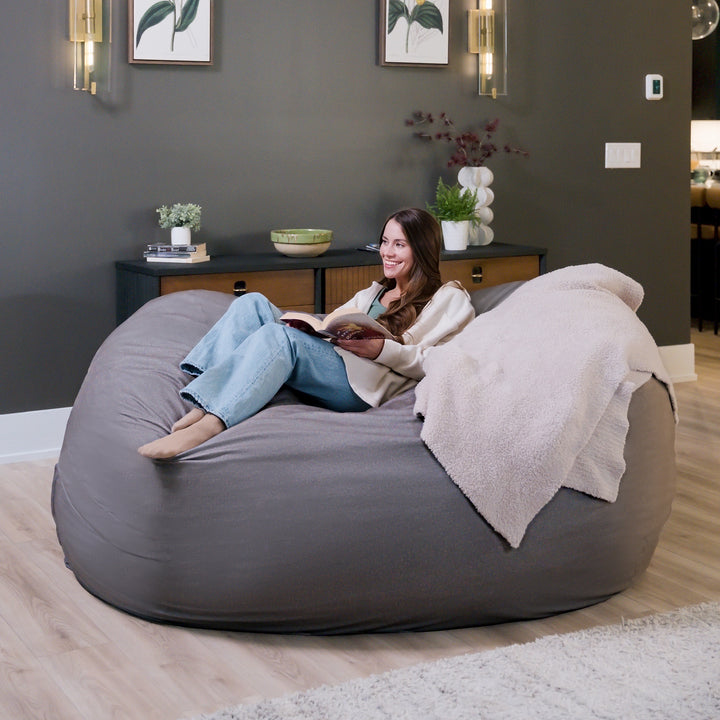 Woman sitting on a large gray bean bag chair in a modern living room. #color_fog-brushed-denim