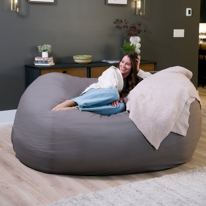 Woman relaxing on a large gray bean bag chair in a cozy living room. #color_fog-brushed-denim