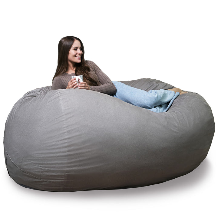 Woman sitting in a large gray bean bag chair holding a mug on a white background #color_fog-brushed-denim