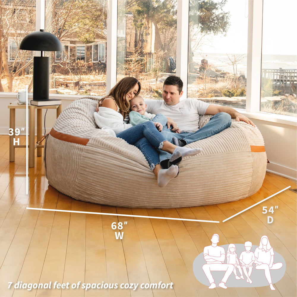 Family sitting on a large bean bag chair with dimensions displayed #color_vanilla-latte-corded-plush
