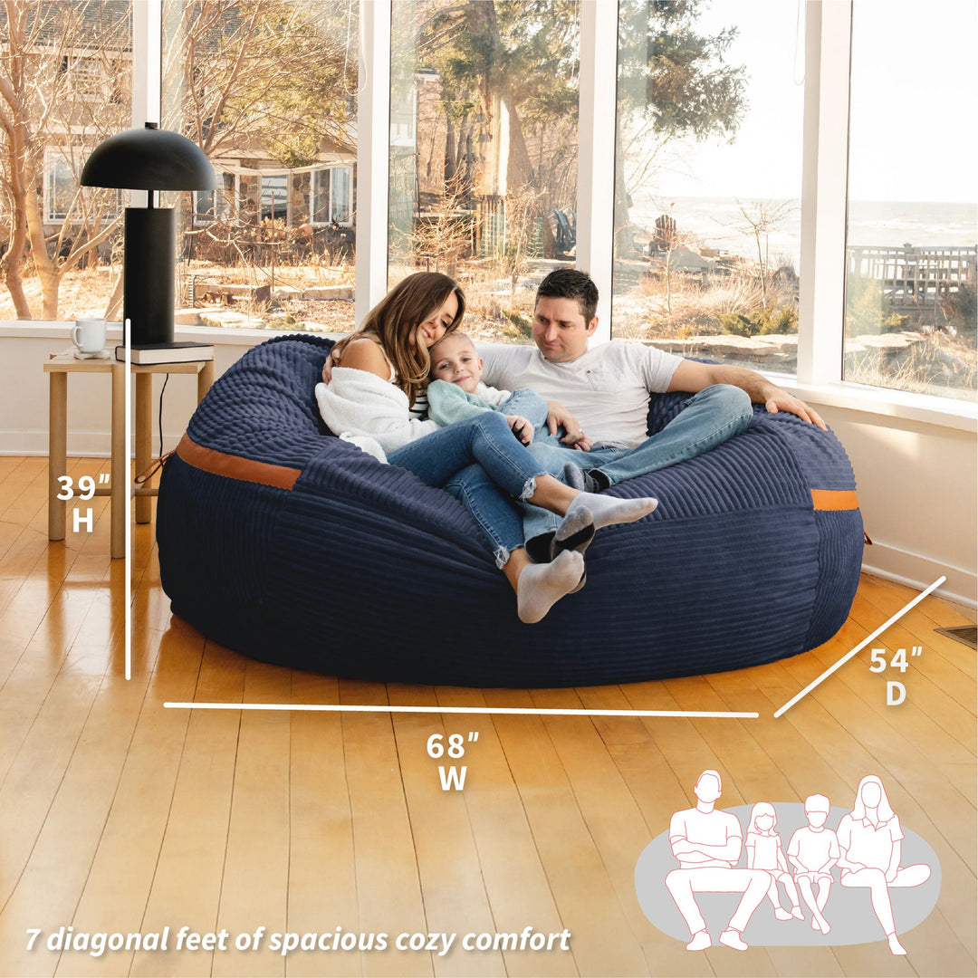 Family sitting on a large navy bean bag with dimensions displayed #color_midnight-blue-corded-plush