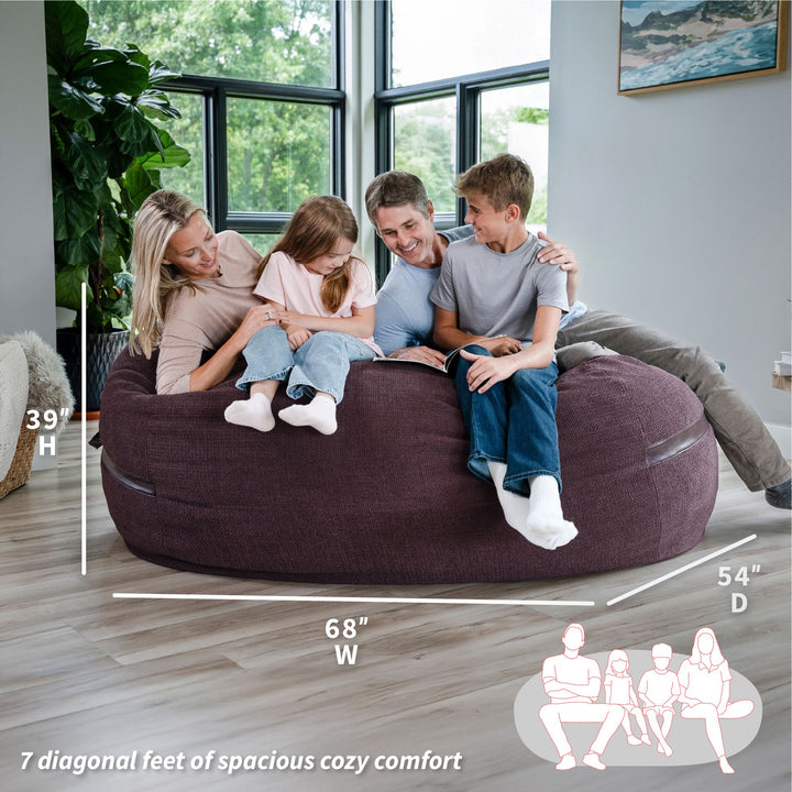 Family sitting on a large bean bag with dimensions displayed #color_merlot-cloudweave
