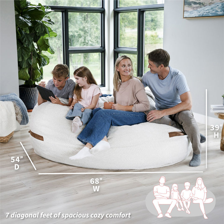 Family sitting on a large bean bag with dimensions displayed #color_sandstone-textured-boucle