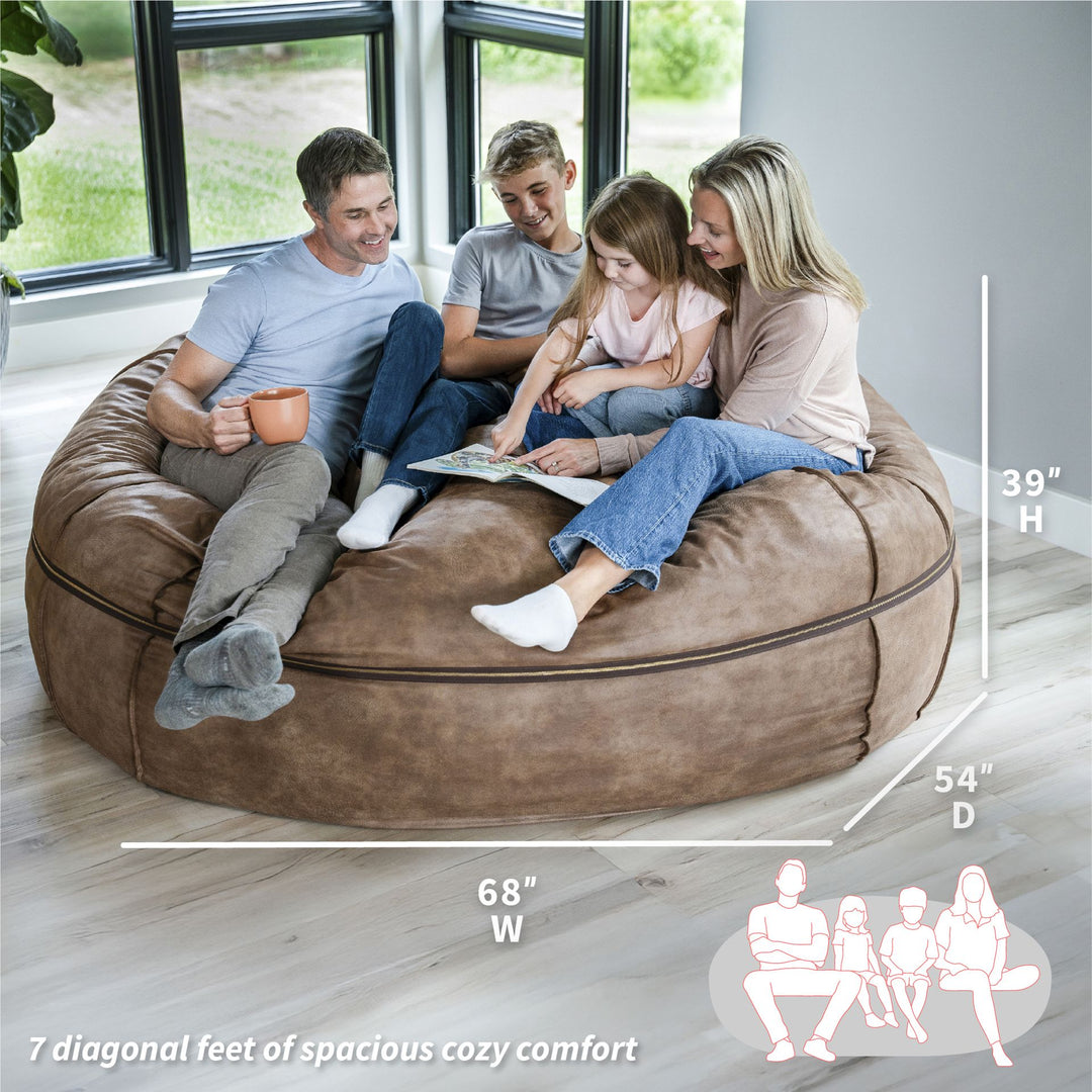 Family sitting on a large brown bean bag with dimensions displayed #color_coffee-soft-vegan-leather