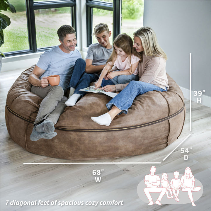 Family sitting on a large brown bean bag with dimensions displayed #color_coffee-soft-vegan-leather