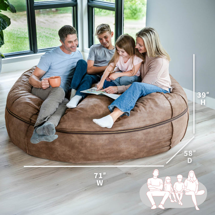Family sitting on a large brown bean bag with dimensions displayed #color_coffee-soft-vegan-leather