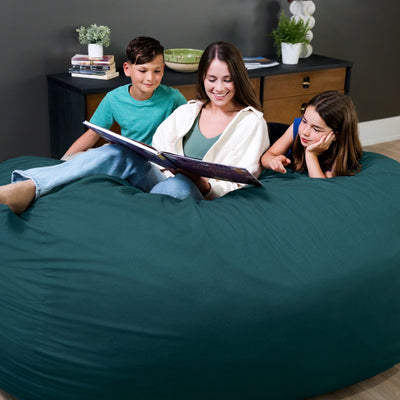 Woman reading a book to two children on a teal bean bag chair. 
