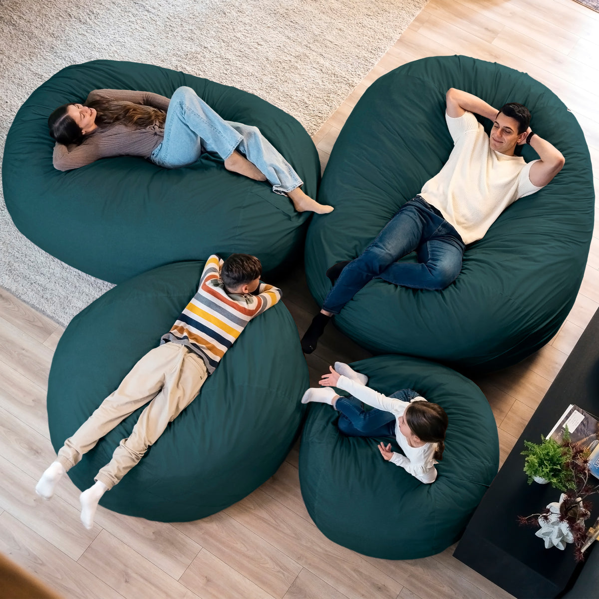 Four people relaxing on green bean bags in a living room. 