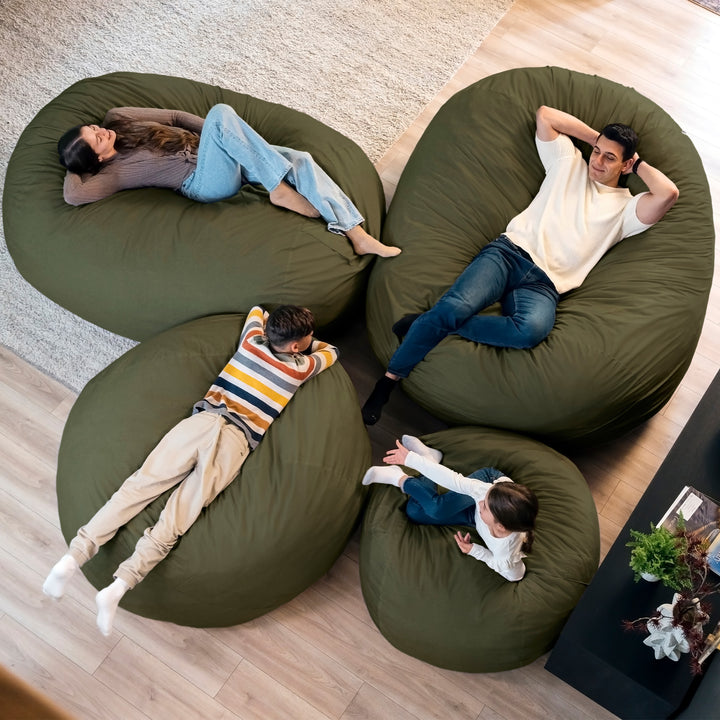 Four people relaxing on large green bean bags in a living room. #color_forest-green-velveteen