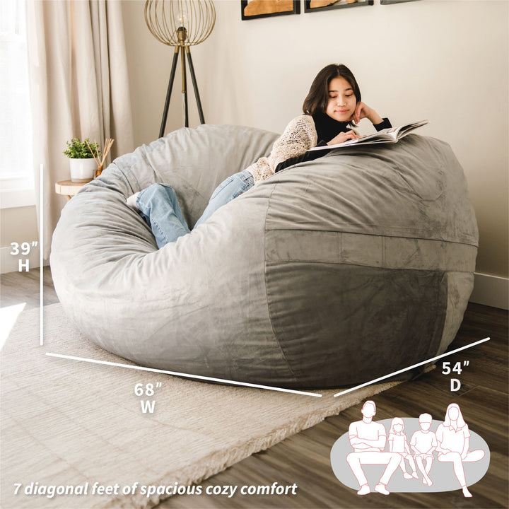 Woman reading a book on a large gray bean bag chair in a cozy living room. #color_gray-plush